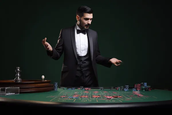 একজন পুরুষ তার ল্যাপটপে মনোযোগ দিয়ে কাজ করছেন, ব্যাকগ্রাউন্ডে লাইভ স্ট্যাটস — যা CROREWIN মোবাইল অ্যাপের স্পোর্টস ও গেমিং ফিচারগুলোকে তুলে ধরে।