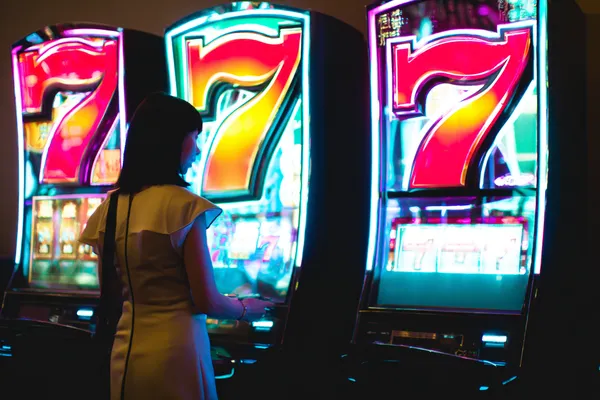 A woman smiling while playing online games on her laptop, surrounded by neon casino elements, showcasing CROREWIN’s diverse game collection.